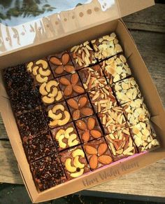 a box filled with lots of different types of nuts and chocolates on top of a wooden table