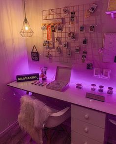 a white desk topped with a laptop computer next to a purple wall covered in pictures