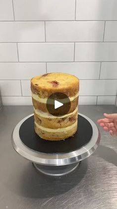 a cake sitting on top of a metal counter next to a person's hand