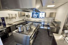 a large commercial kitchen with stainless steel appliances and pots on the stove top ovens