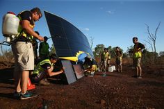 several men in yellow vests are working on a solar panel