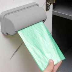 a person is holding a roll of toilet paper in front of a door with a green tissue dispenser on it