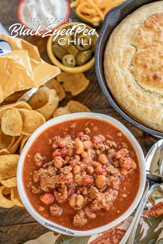 a bowl of chili with bread and chips on the side