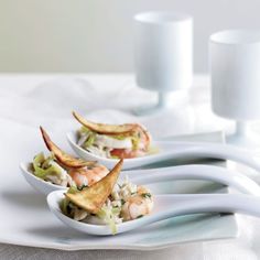 three white spoons with food in them on a table