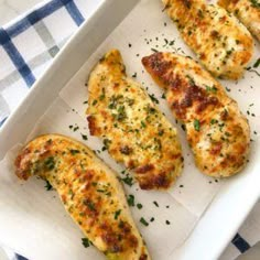 four pieces of chicken sitting on top of a white tray