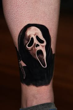 a person with a black and white tattoo on their arm that has a ghost mask in it