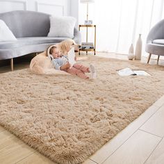 a baby and a dog laying on a rug in a living room with couches