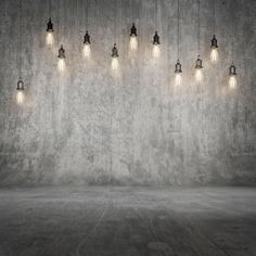 an empty room with many light bulbs hanging from the ceiling and concrete wall behind it