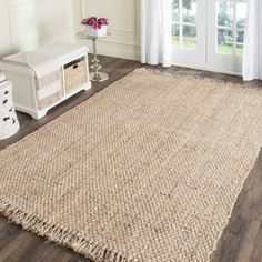 a large rug with fringes on the floor next to a white bench and window