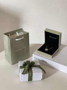 a gift box with a green ribbon tied around it next to a small present box