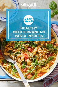 a bowl filled with pasta and spinach on top of a blue plate next to a spoon