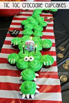 cupcakes with green icing are on a red and white striped table runner