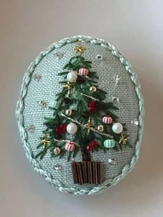 a small christmas tree with ornaments on it's side in a round frame, hanging from the wall