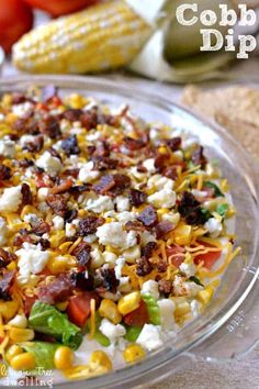 a glass bowl filled with corn, bacon and cheese