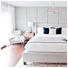 a bedroom with white walls and wood floors is pictured in this image, the bed has blue pillows on it