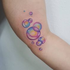 a woman's arm with colorful bubbles on it