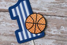 a blue and white number one shaped cake with a basketball on it's stick