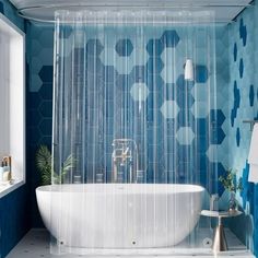 a white bath tub sitting next to a window in a blue and white tiled bathroom