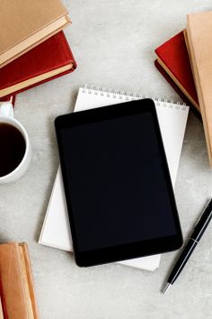 a tablet computer sitting on top of a table next to books and a cup of coffee