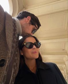 a man and woman standing next to each other in front of a white building with windows