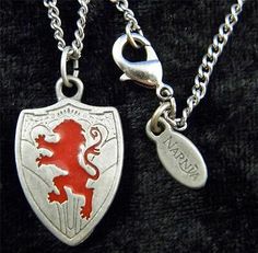 two silver and red lions pendants on a black velvet surface, one with a chain attached to it