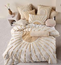 a bed with white and gold comforters on top of it in front of a wall