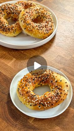 two white plates topped with bagels on top of a wooden table