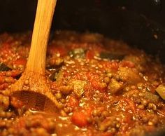 a wooden spoon stirring some food in a pot