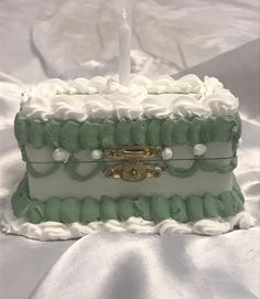 a white and green cake with gold decoration