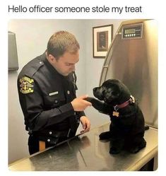 a police officer petting a black dog on the nose in front of a mirror