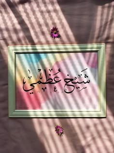 an arabic calligraphy written in two different languages on a pink and blue background with flowers