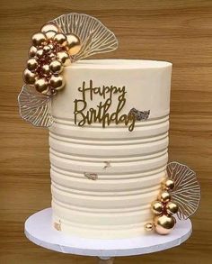 a white cake with gold decorations on it and happy birthday written on the top tier