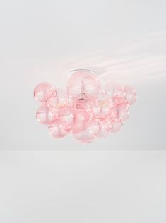 a ceiling light with pink glass balls hanging from it's center point, on a white background