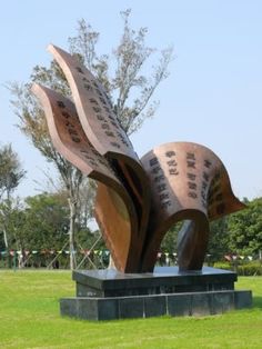 a large metal sculpture sitting on top of a lush green field