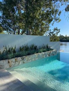 an empty swimming pool in front of a white fence and trees with water running through it