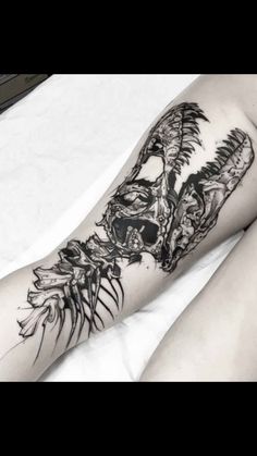 a woman's leg with tattoos on it and an image of a demon in the background