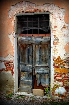 an old building with two wooden doors in front of brick wall and window sill