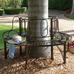 a bench sitting under a tree next to a planter with a hat on it