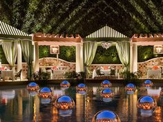 an outdoor dining area is lit up at night with lights reflecting off the water and candles on the ground