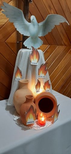 a table topped with two vases and a lit candle next to a bird statue