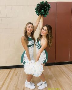 two girls in cheerleader outfits holding pom poms and posing for the camera