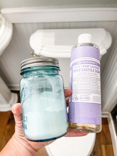 a person holding a blue mason jar next to a purple and white toilet paper roll