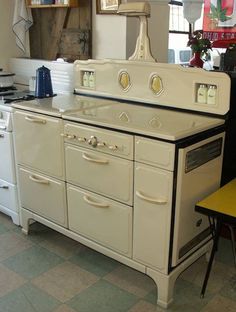 an old fashioned white stove and oven in a kitchen with yellow table cloth on the floor