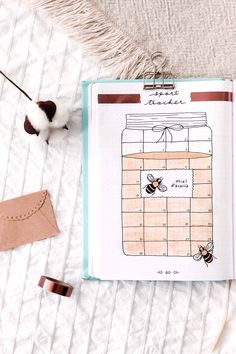 an open notebook with a drawing of a jar and bees on it next to some other items