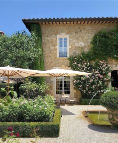 an outdoor area with tables and umbrellas in front of a building that has flowers growing on it