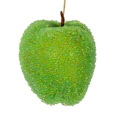 an apple shaped ornament is hanging from a rope on a white background with green speckles