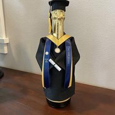 a bottle with a graduation cap on it sitting on a table next to a wall