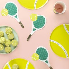 tennis balls and rackets are on plates with paper cutouts in the shape of tennis racquets