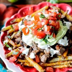 a red plate topped with fries covered in toppings