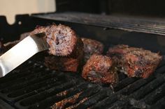 meat is being cooked on the grill with a knife